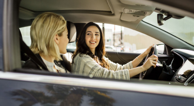 A Lyft driver smiling as a passenger in the front seat.