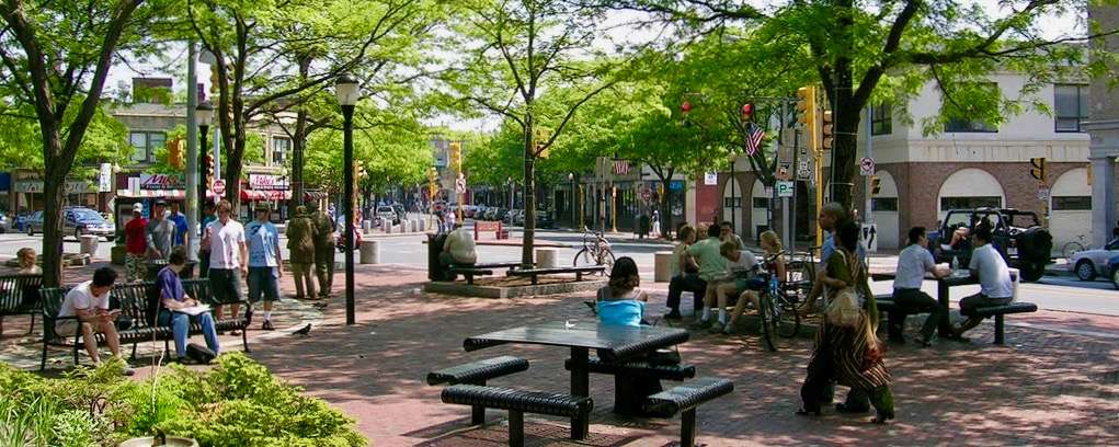 Image of Davis Square with people sitting on benches and at tables.