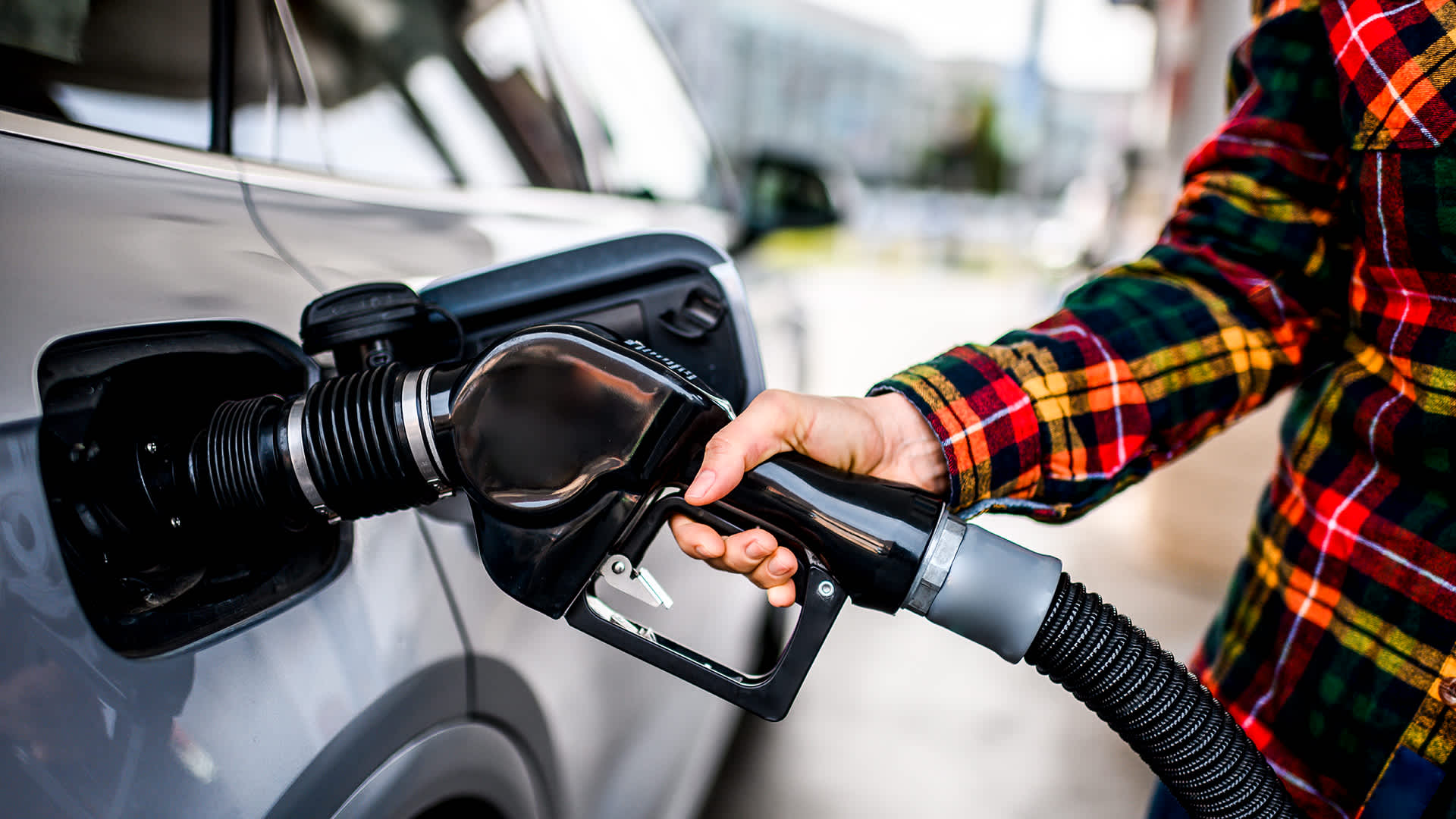 An image of a person's hand holding a gas pump up to a vehicle. Credit: Getty Images.