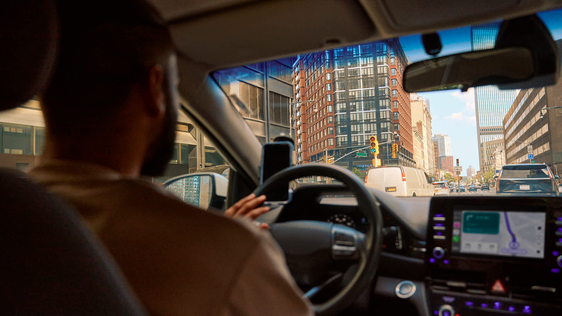 Man driving a car in the city. Header image for Lyft article on "The real cost of getting around in 2026: Rideshare vs. car ownership"