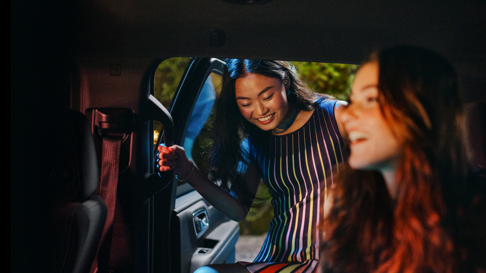 Smiling passenger entering a Lyft ride with a friend already in the car. 