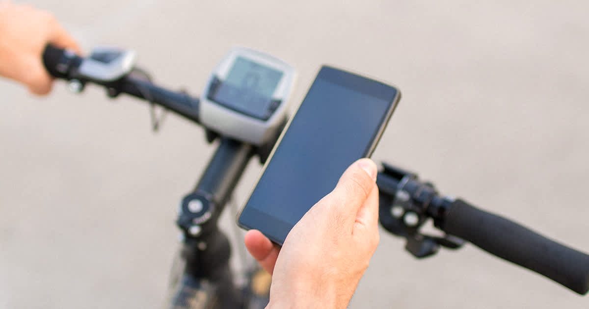 Image of a person holding up a smartphone over their e-bike,