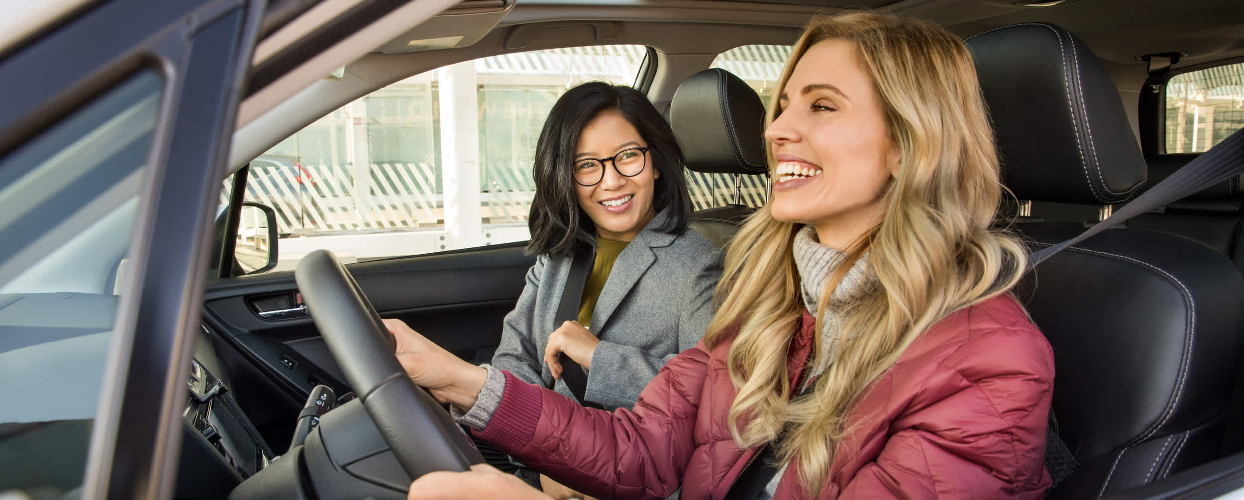 A female Lyft driver laughing with a female Lyft passenger.