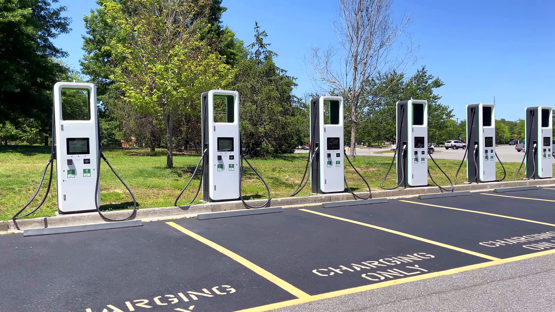 Photograph of a bank of electric vehicle charging kiosks. Parking spaces read "Charging Only"