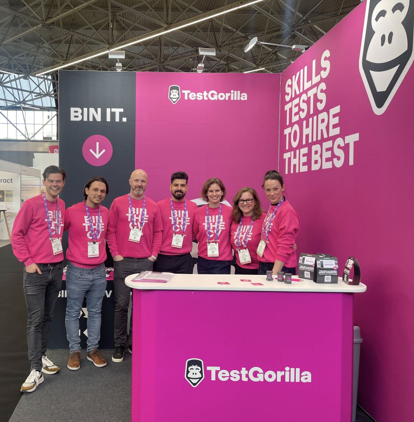 members of the TestGorilla team stand in pink jumpers that say 'bin the CV' on them