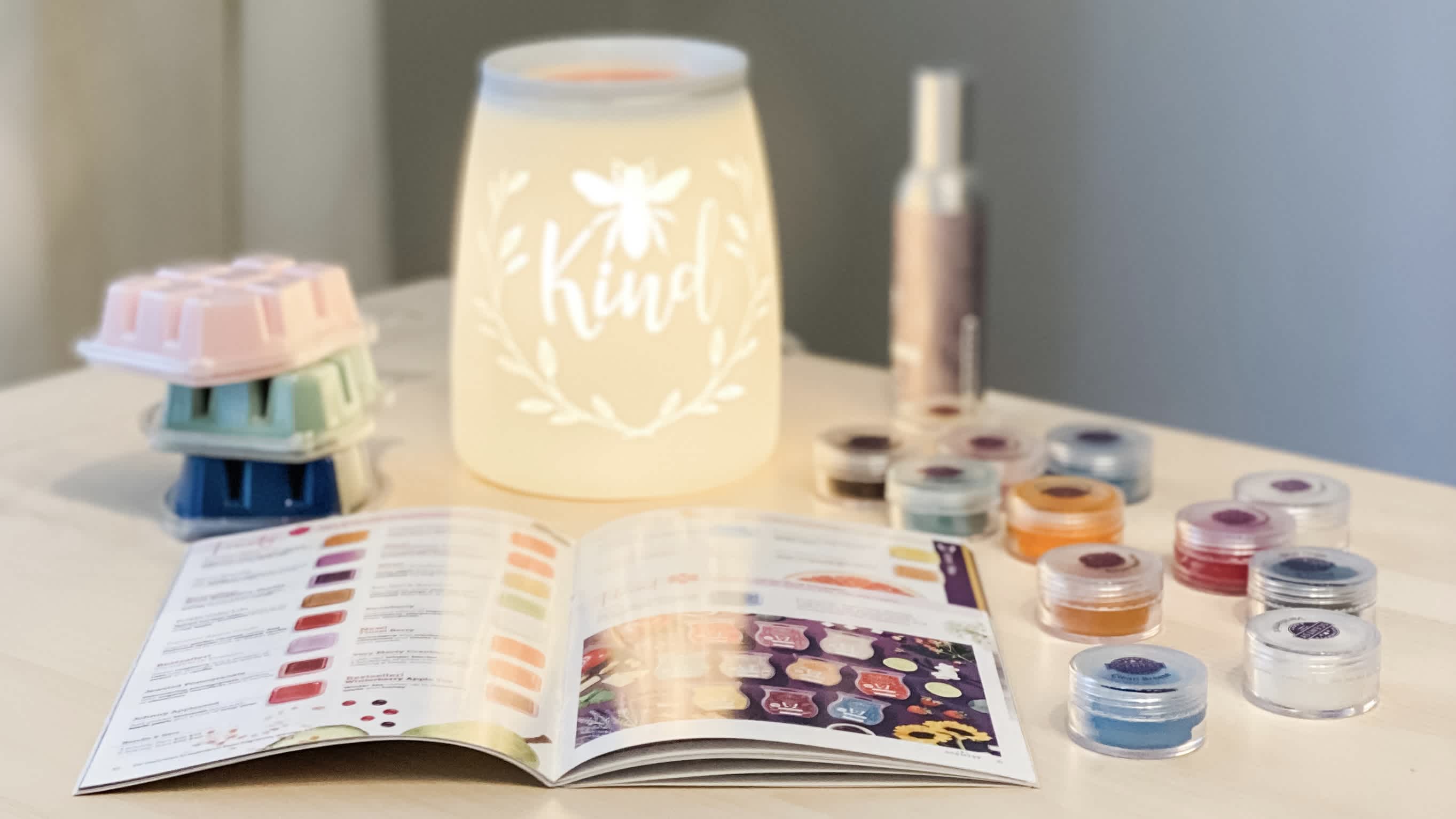 Picture of Scentsy catalog, wax bars, Kindness warmer, wax testers, and room spray on table
