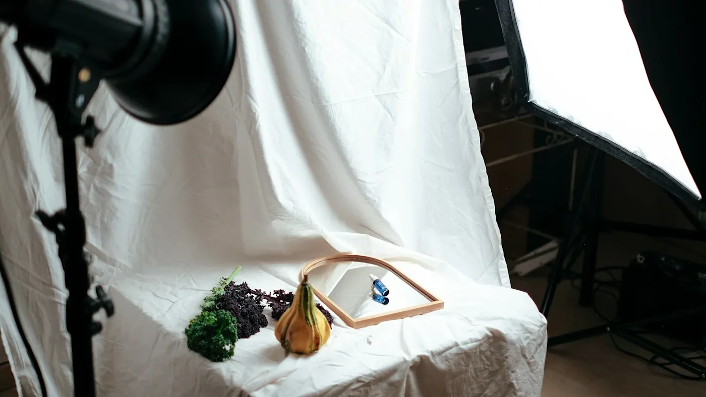 A small home studio set up to photograph products: a white backdrop, two lights and a few items arranged on a table