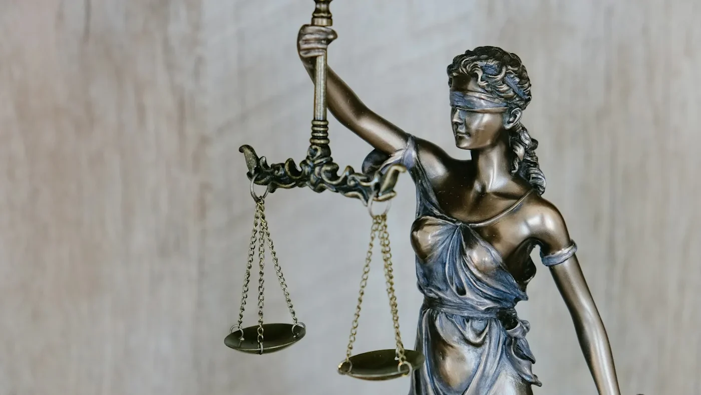 A bronze statue of blindfolded Justice holding the scales