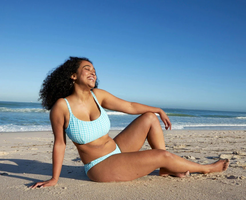 Femme assise sur une plage avec la mer en arrière-plan