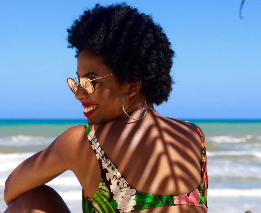 African woman with sunglasses smiling on the beach