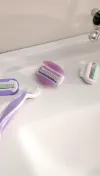 Rasoir rechargeable mauve Venus de Gillette avec une tête de rasoir détachée et deux autres têtes de rasoir à côté