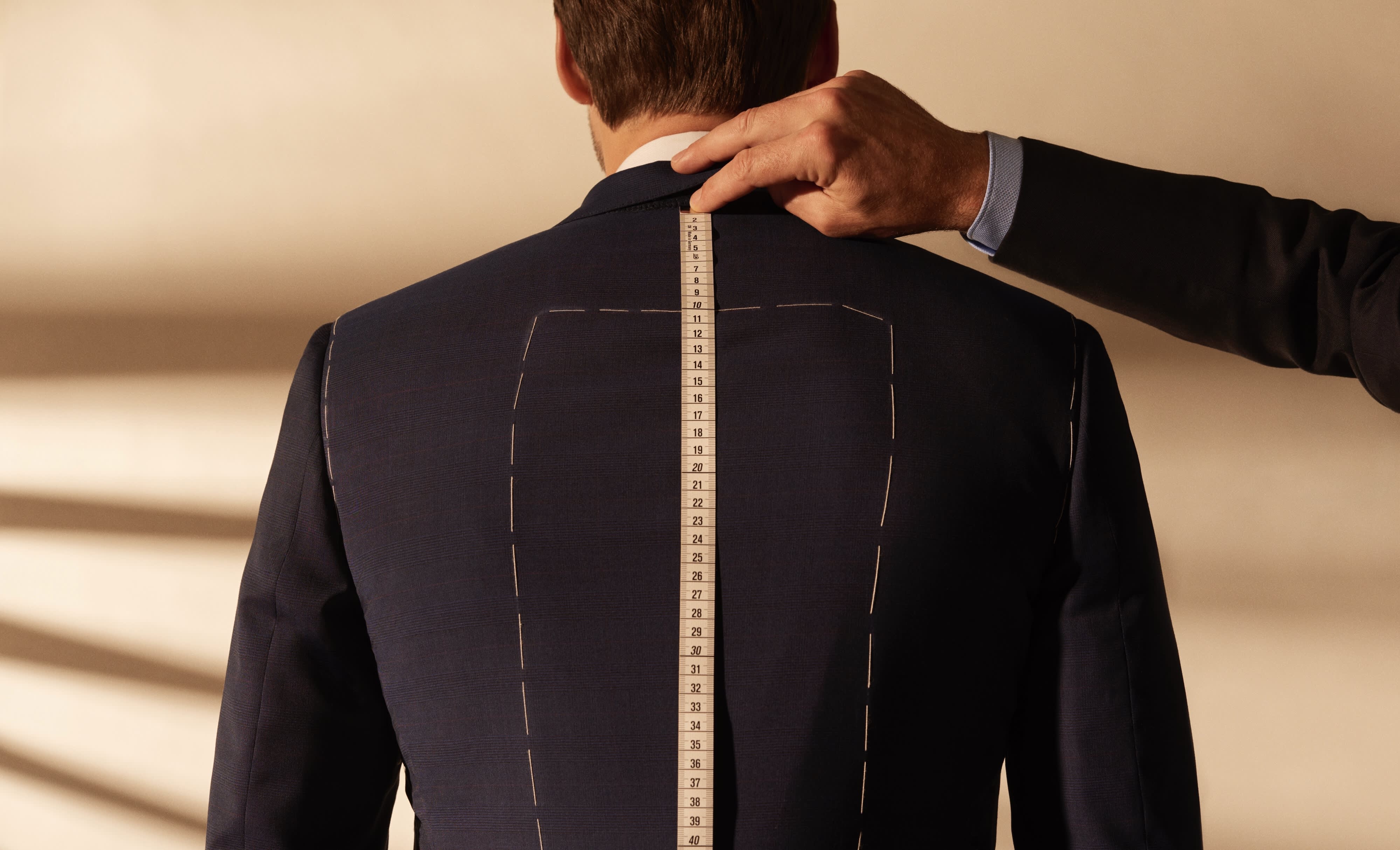 A Brioni master tailor taking the measurements of a client