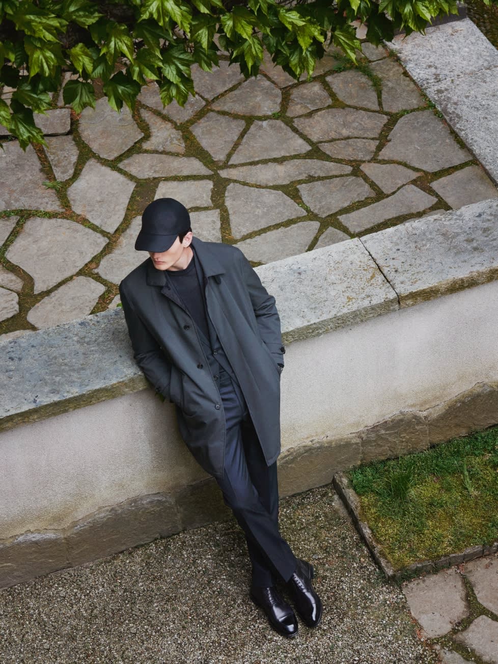Male model wearing a Brioni dark grey coat and baseball hat