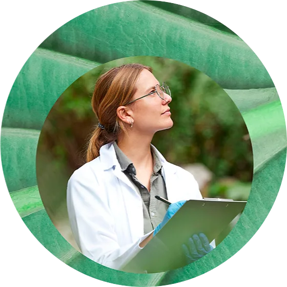 Scientifique observant la nature tout en prenant des notes, vêtue d'une blouse blanche et de gants bleus, entourée de feuilles vertes