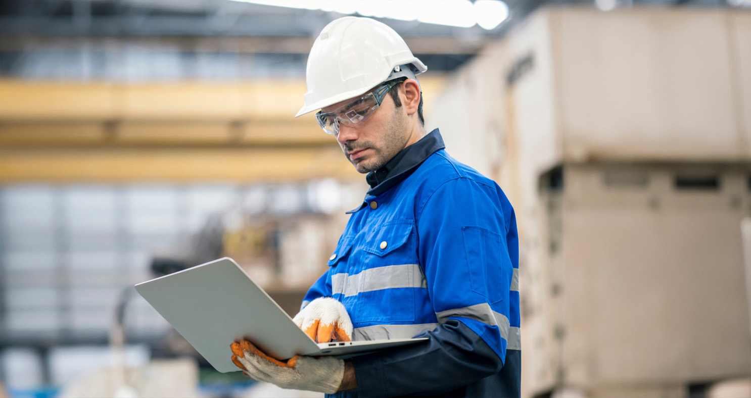 Supervisor reviewing data over laptop on factory floor