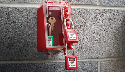 Safety Lockout Box locked by padlocks on concrete wall