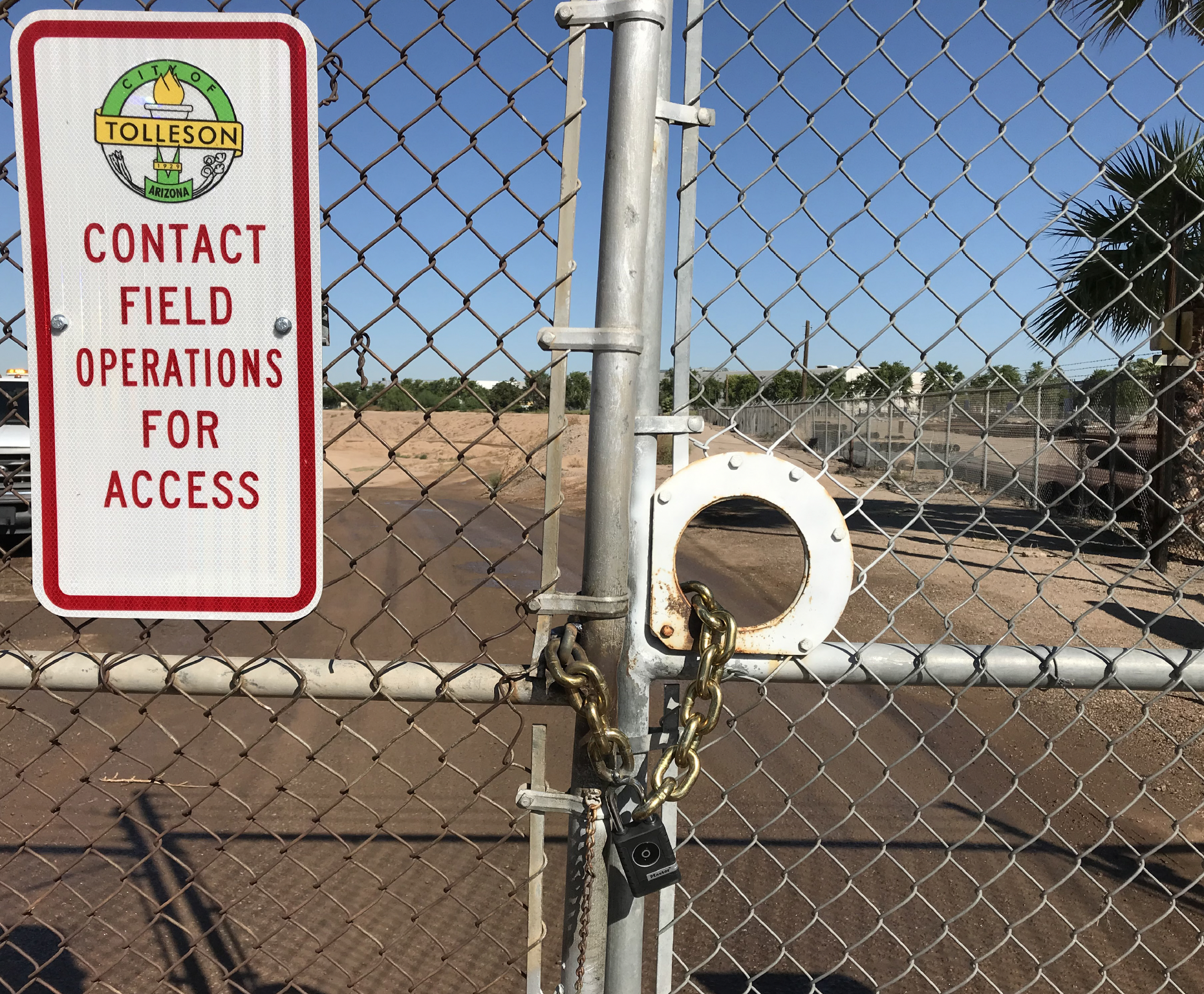 A fence with a city of tolleson sign that reads "contact field operations for access"