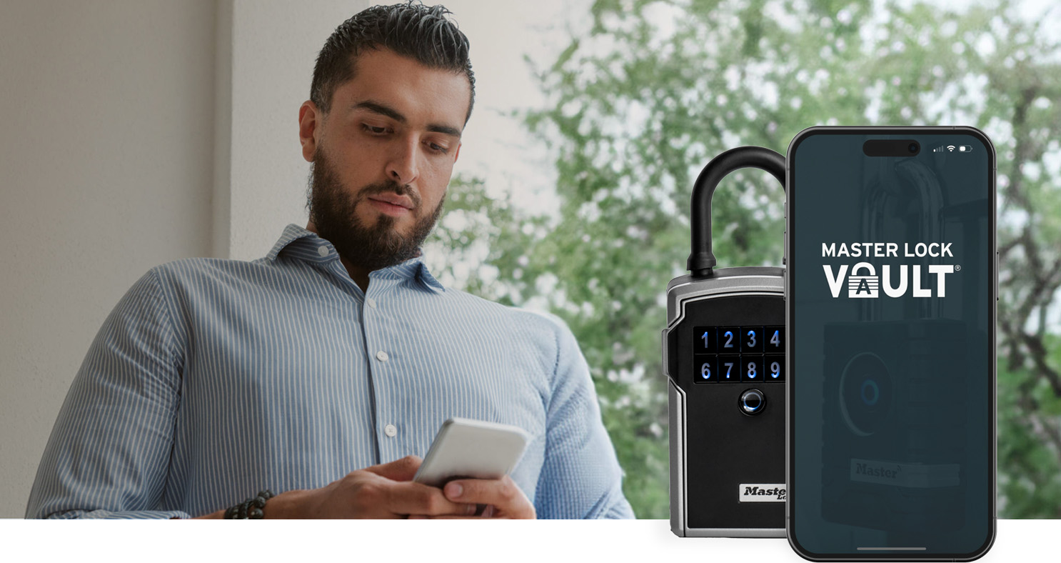 A man looking at his phone while using master lock vault