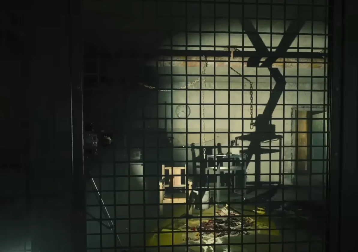 A room visible through grates, softly lit, with damaged furniture inside.
