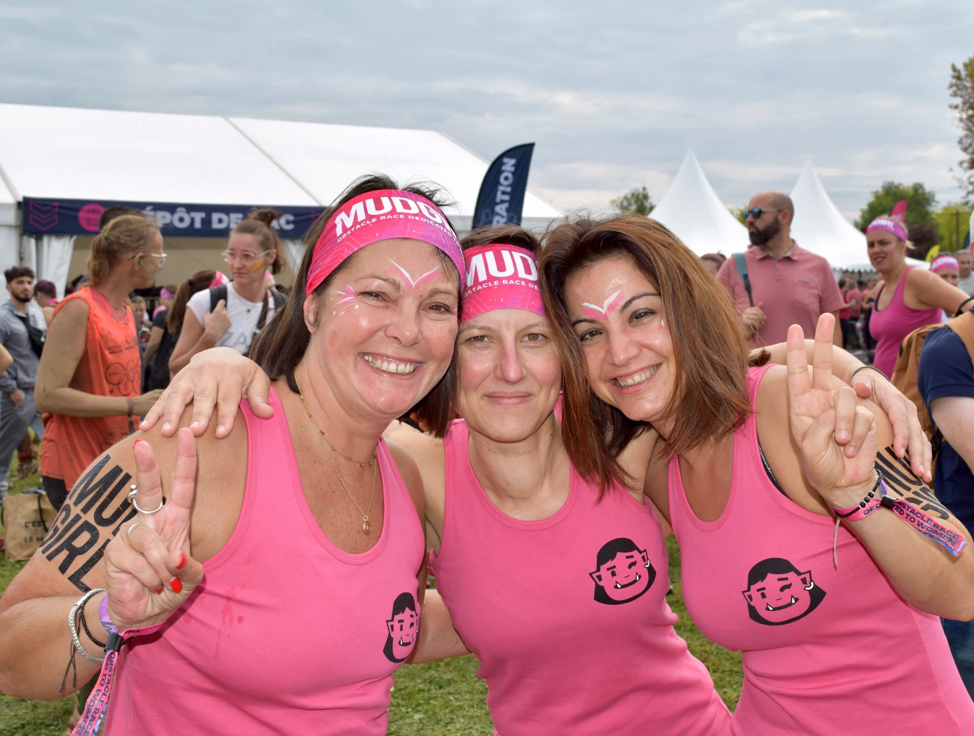 A group of women posing to a picture after the successful race in breast cancer awareness meeting. They all wear pink shirts and pink headbands.