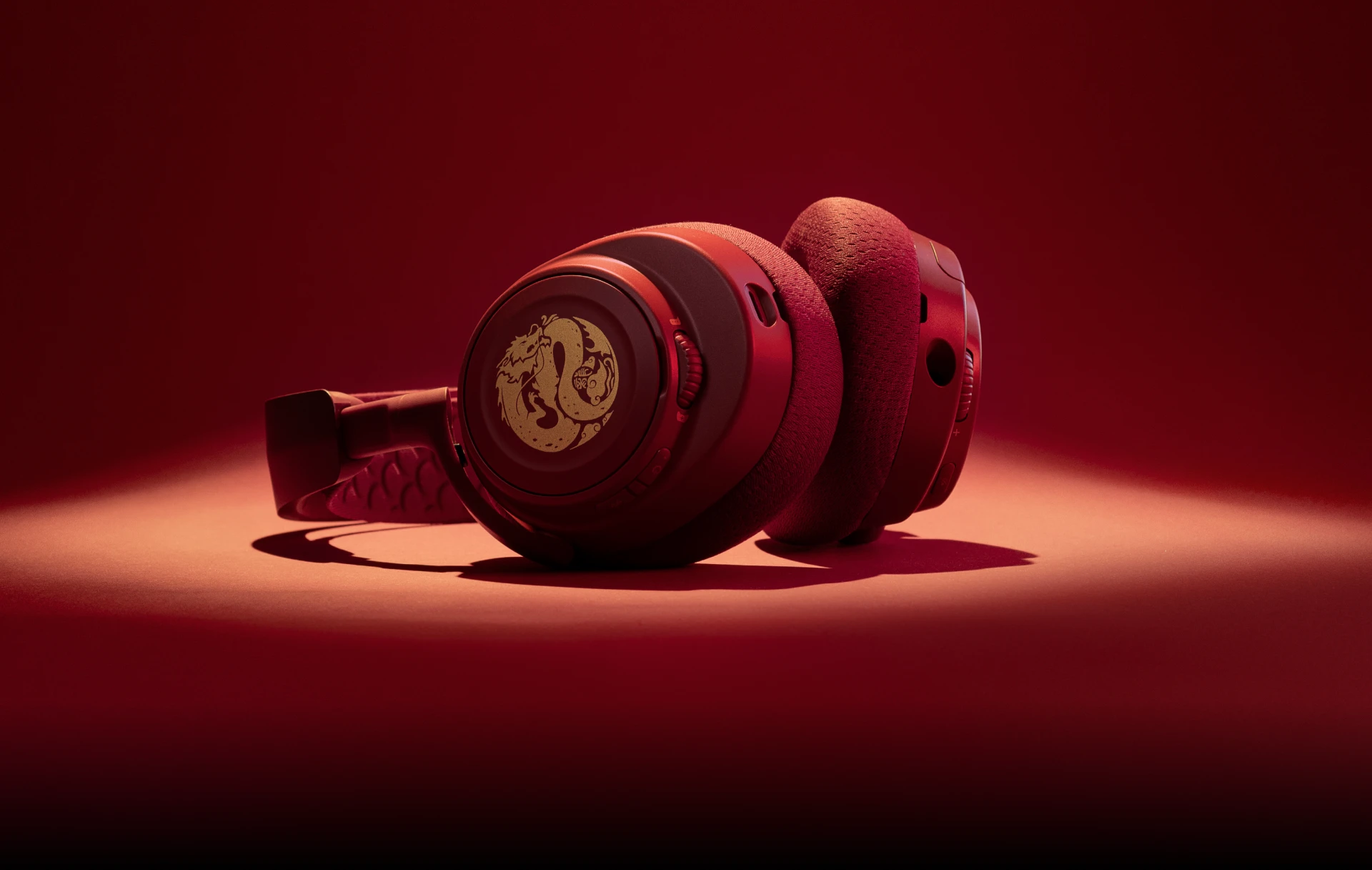 An Arctis Nova 7 Dragon Edition headset laying on its side framed by dramatic lighting.