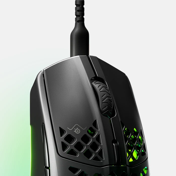 A close-up of a black gaming mouse with a honeycomb design and green light glowing from inside.
