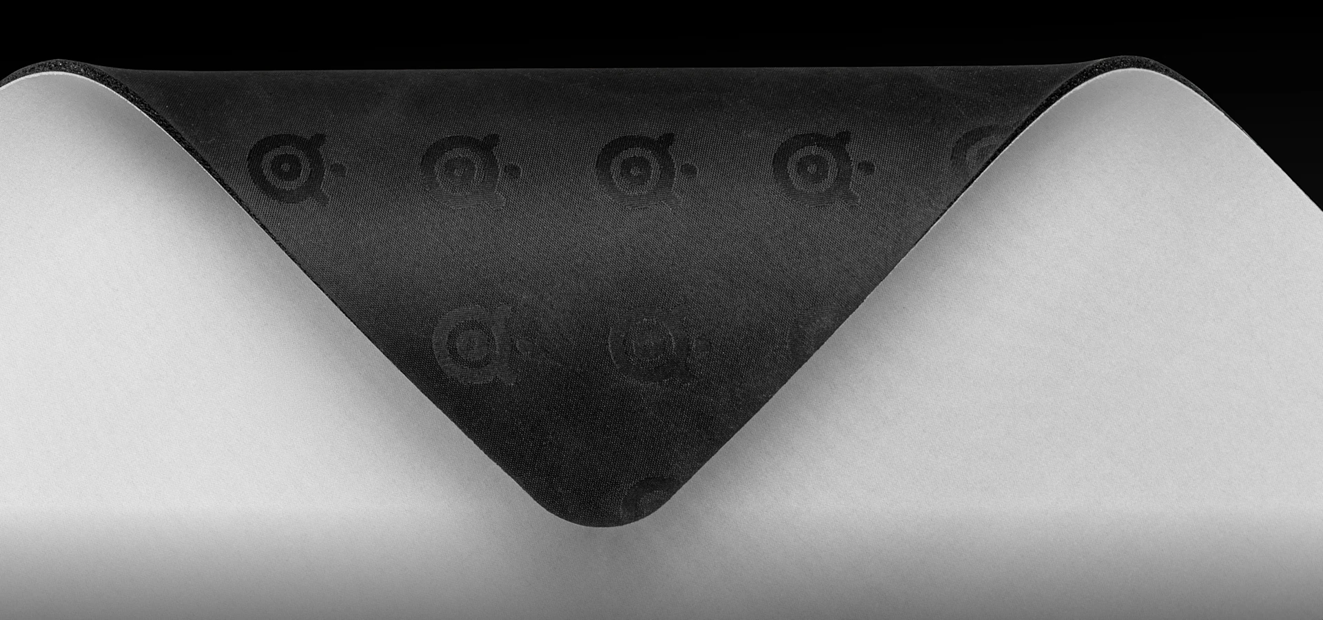 Close-up of the SteelSeries QcK Heavy XXL mousepad showing the non-slip rubber base with embossed SteelSeries logos designed to prevent unwanted movement during gaming.