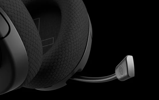 En närbild av ett svart gamingheadset med texturerade hörlurar och flexibel mikrofon, som framhäver det bikakemönstrade tyget mot en helt svart bakgrund.