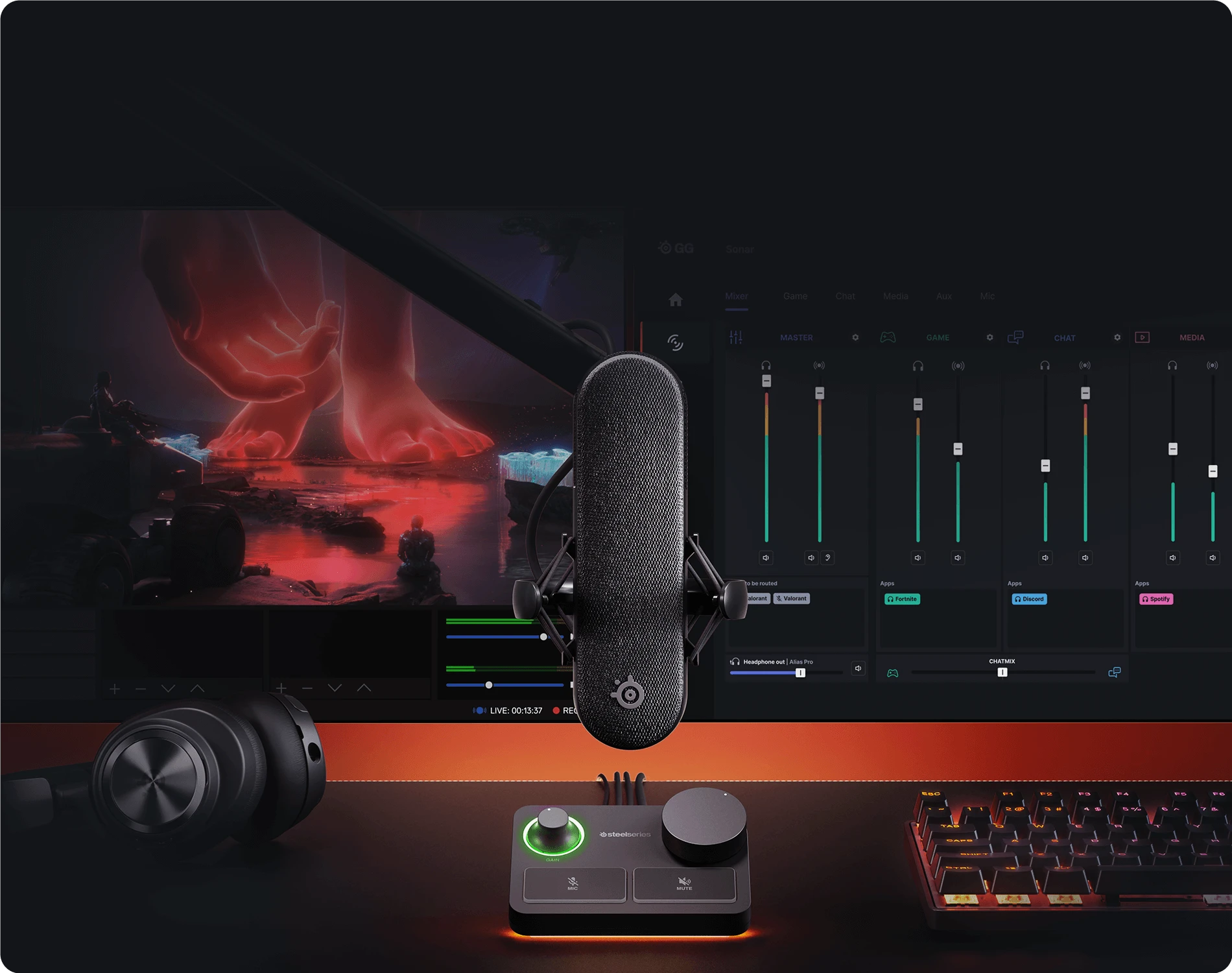 A professional streaming setup with a SteelSeries microphone and audio mixer, headphones, and a keyboard in front of a large monitor.