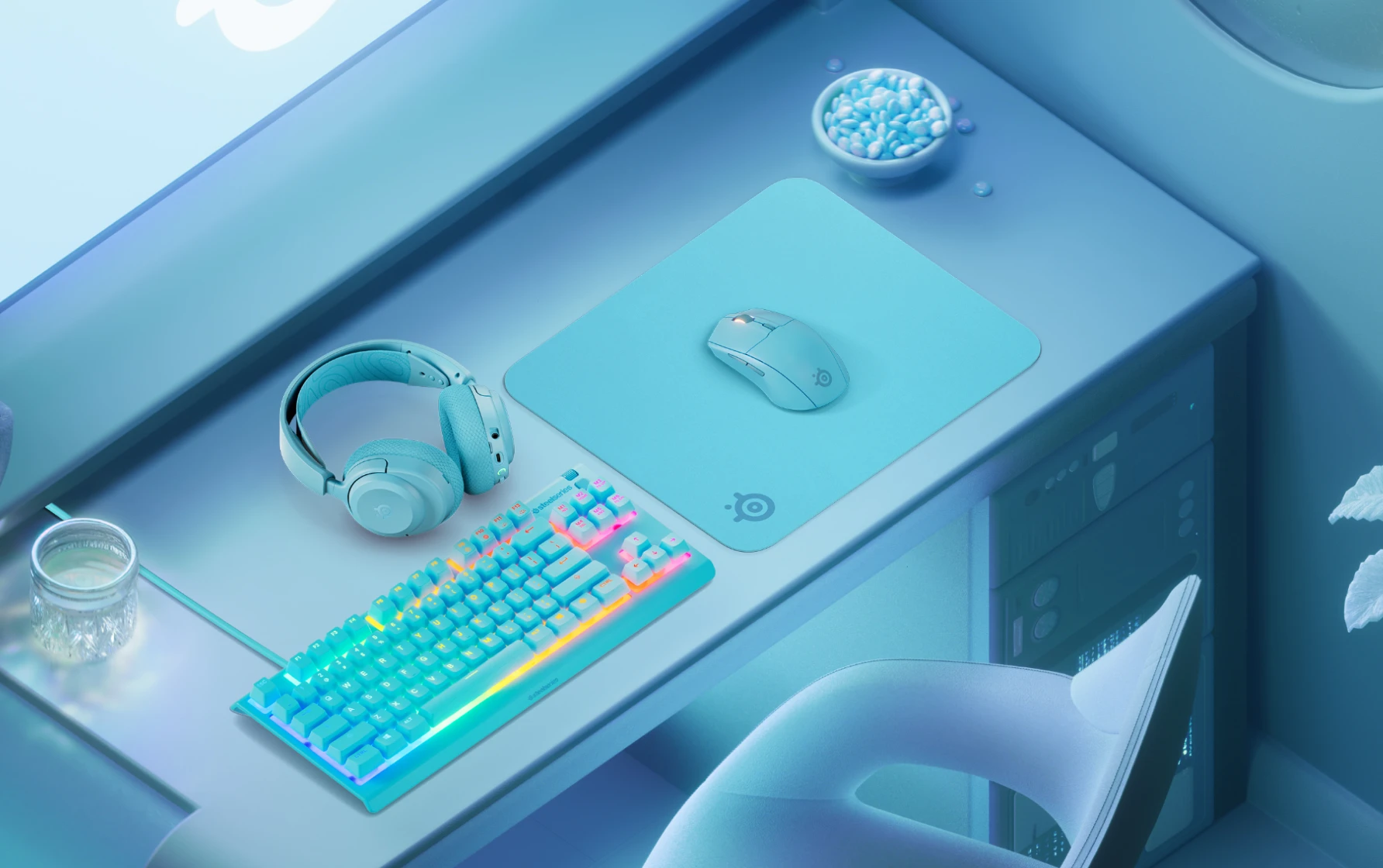 En snygg, ljusblå speluppsättning med matchande RGB-tangentbord, mus, SteelSeries-musmatta och hörlurar som är snyggt arrangerade på ett skrivbord.