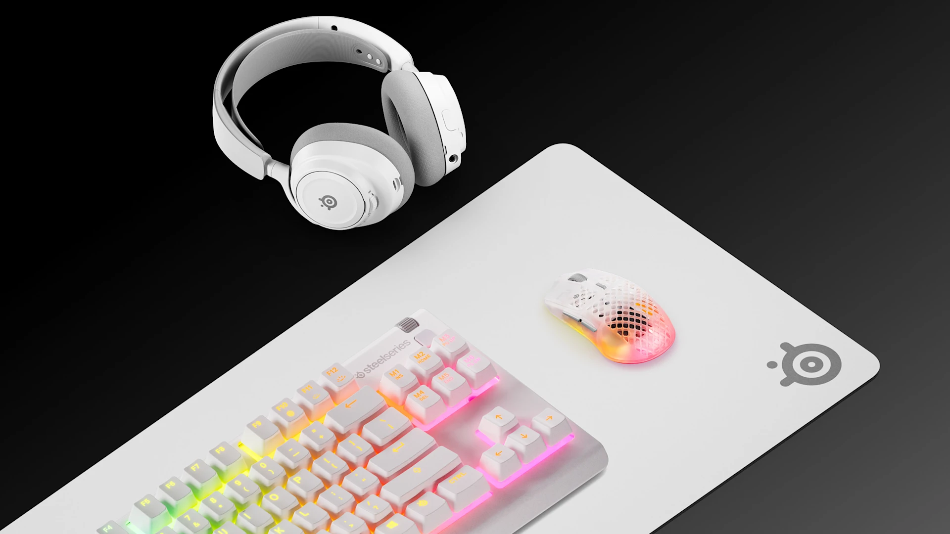 An isometric view of a complete white SteelSeries gaming setup featuring the QcK Heavy XXL mousepad, Apex 7 TKL White keyboard, Arctis Nova 7 White headset, and Aerox 3 Wireless mouse on a black surface.