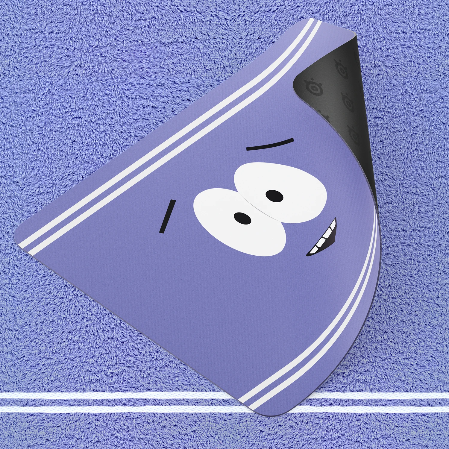 SteelSeries Towelie special edition gaming mousepad shown with a folded corner to reveal its non-slip rubber base, placed on a textured purple towel background.