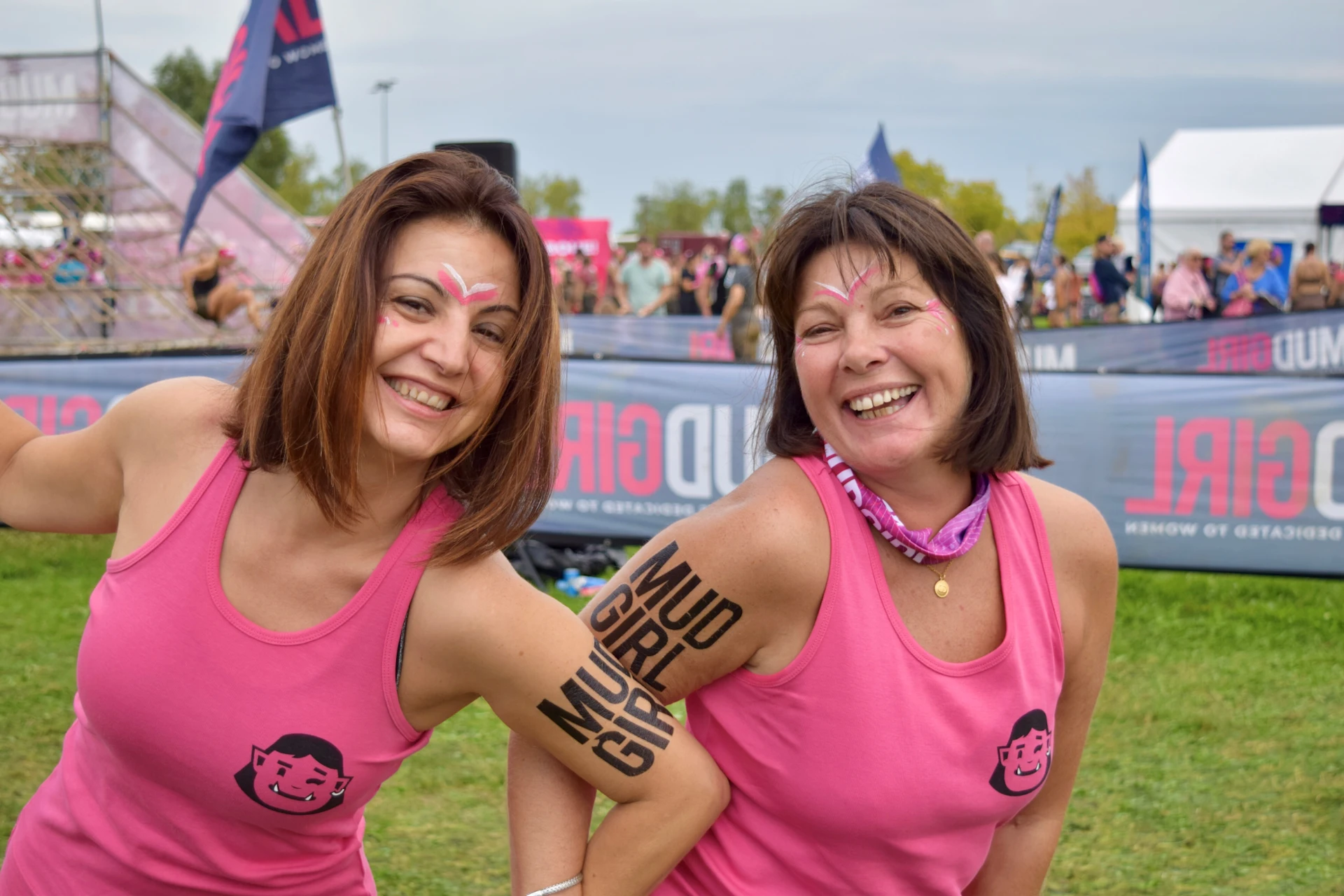 Two women with mudgirl tattoo on their arms looking very happy after the run race.