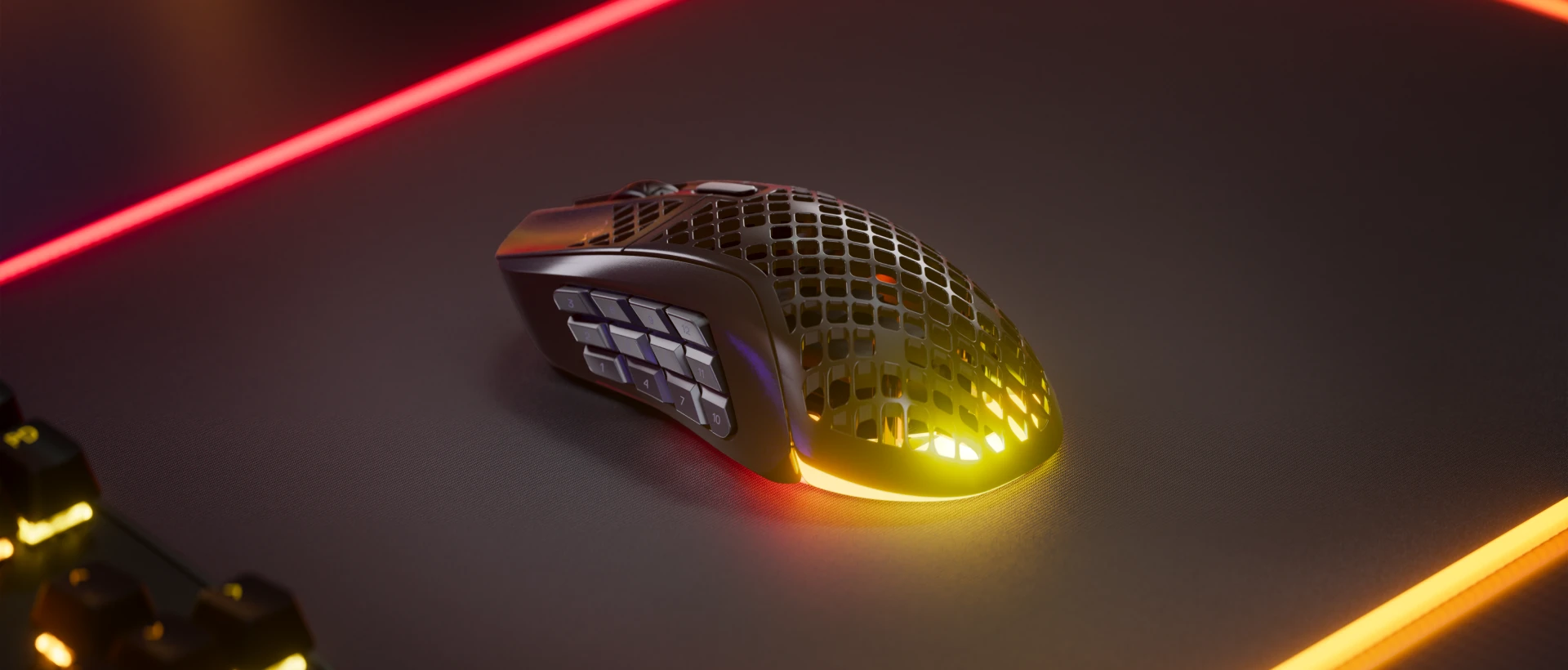 Vista de un Aerox 9 Wireless desde la parte superior izquierda sobre una alfombrilla de ratón. Podemos ver el botón de 18 programables en el lado izquierdo de los ratones