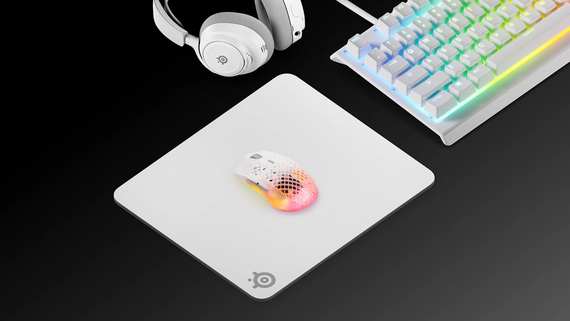 Widok izometryczny klasycznego, białego zestawu gamingowego SteelSeries, w skład którego wchodzą podkładka pod mysz QcK Heavy L, klawiatura Apex RGB, białe słuchawki Arctis Nova oraz biała mysz bezprzewodowa Aerox 3.