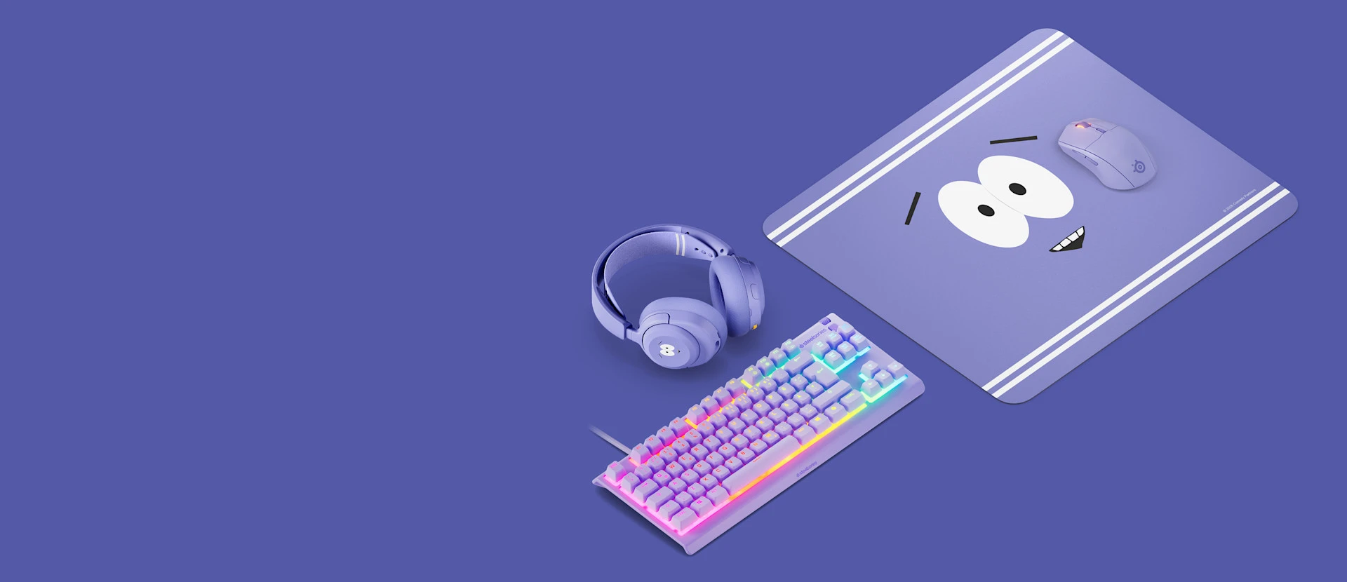 SteelSeries Towelie edition purple gaming gear setup including a large cloth mousepad, matching wireless gaming mouse, Arctis Nova headset, and an illuminated RGB mechanical keyboard.