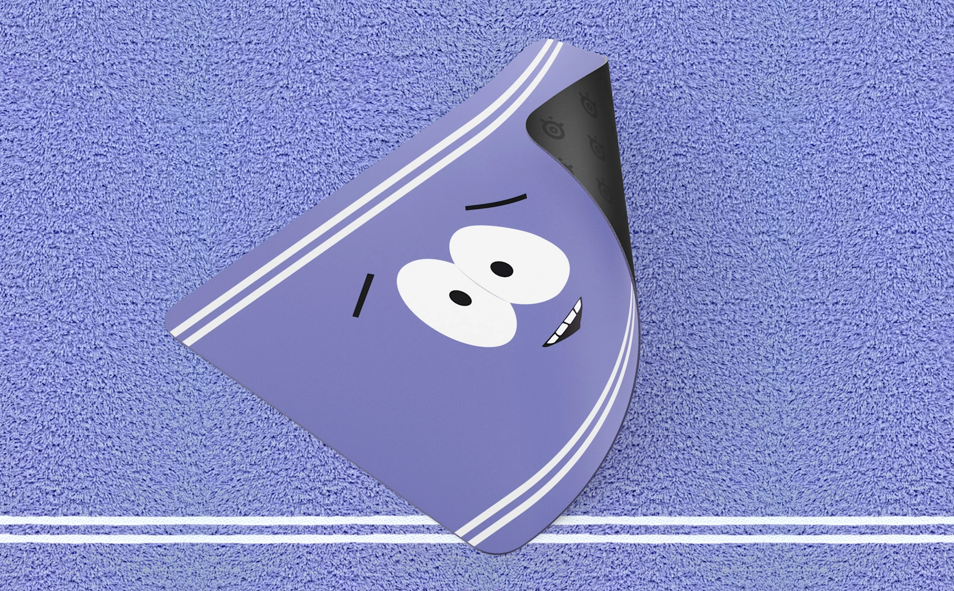 SteelSeries Towelie Gaming-Mauspad in Sonderausgabe, abgebildet mit umgeschlagener Ecke, um die rutschfeste Gummibasis zu zeigen, platziert auf einem strukturierten violetten Handtuchhintergrund.