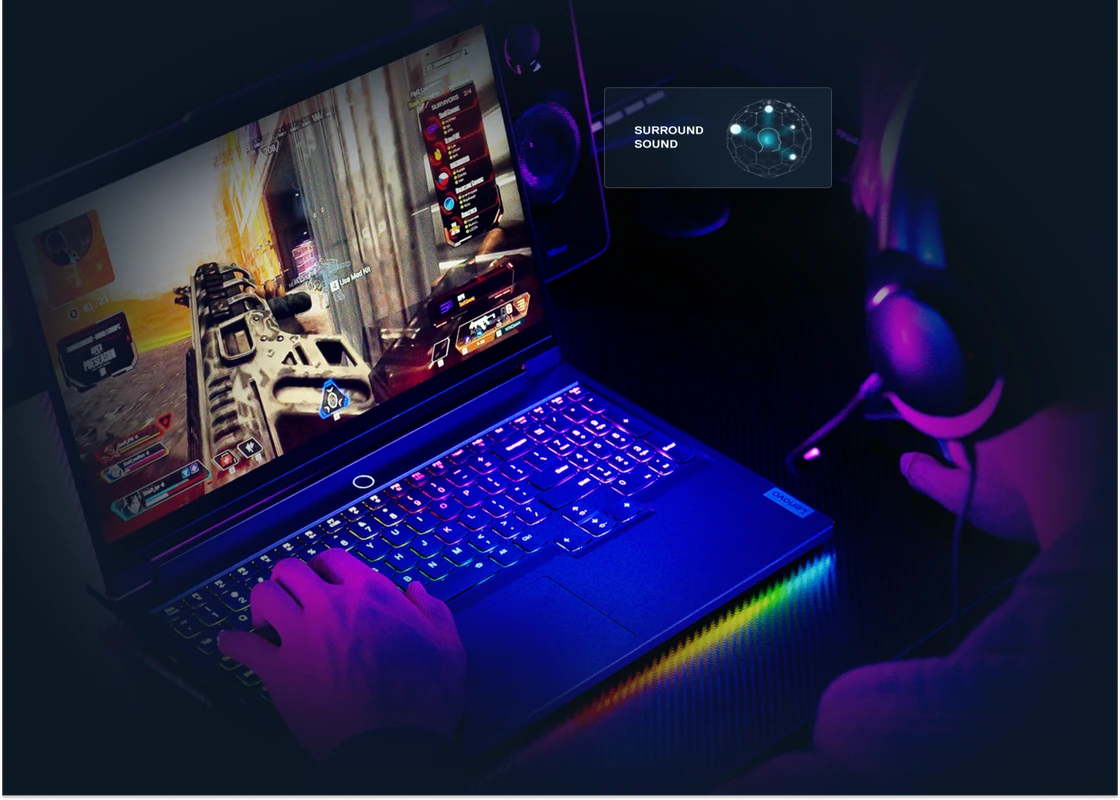 A person plays a video game on a Lenovo Legion laptop with a brightly lit keyboard. An overlay graphic illustrates the "SURROUND SOUND" feature.