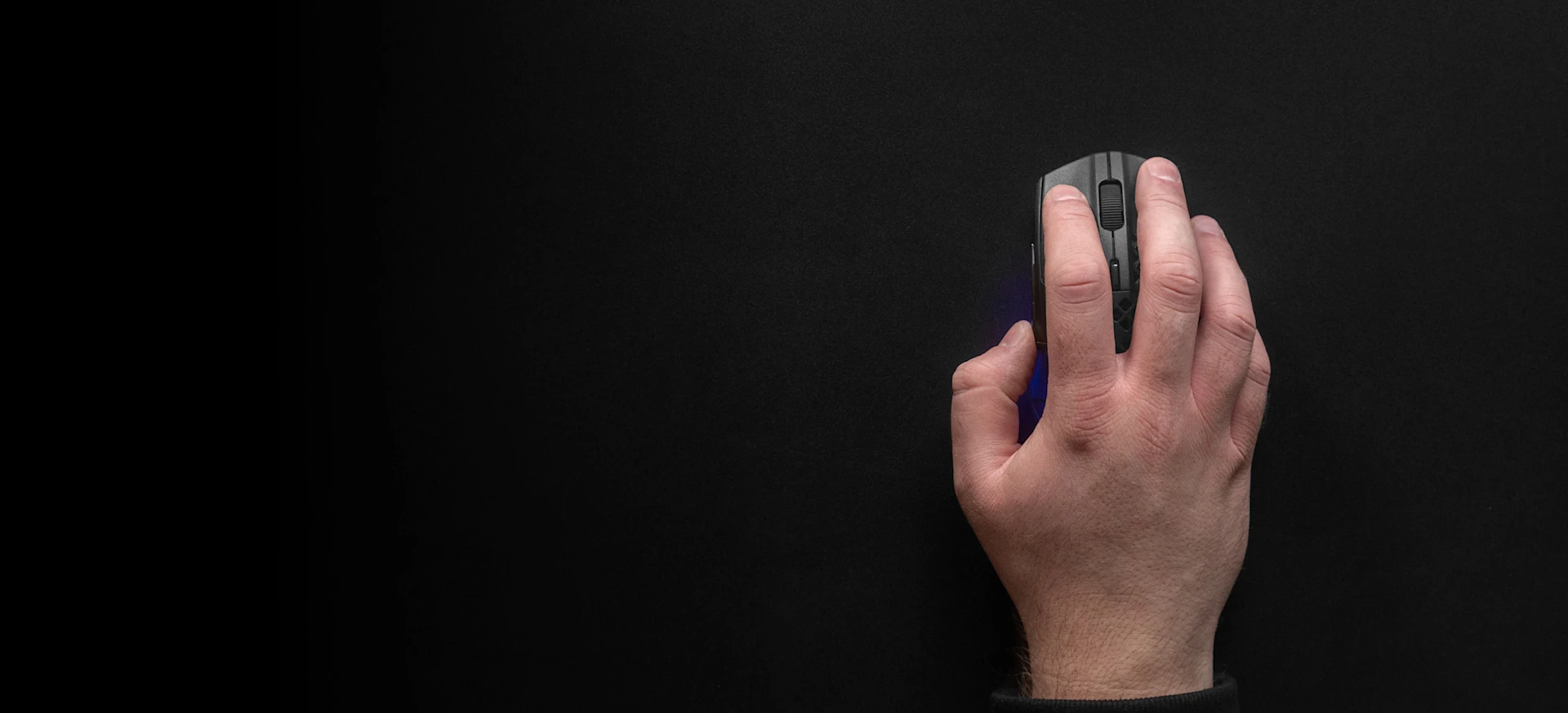Top-down view of a hand using a black gaming mouse on a large, smooth black QcK mousepad.