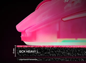 Et nærbillede fra siden, der viser tykkelsen på 6 mm på SteelSeries QcK Heavy XXL-musemåtten sammenlignet med tyndere standardmåtter, med en magenta gamingmus placeret ovenpå.
