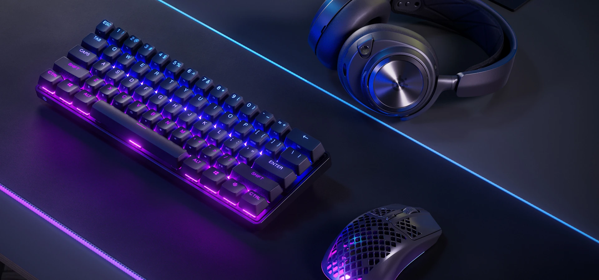 apex pro mini wirelsss en couleurs rgb foncées accompagné d'une souris et d'un casque, sur tapis de souris rgb.