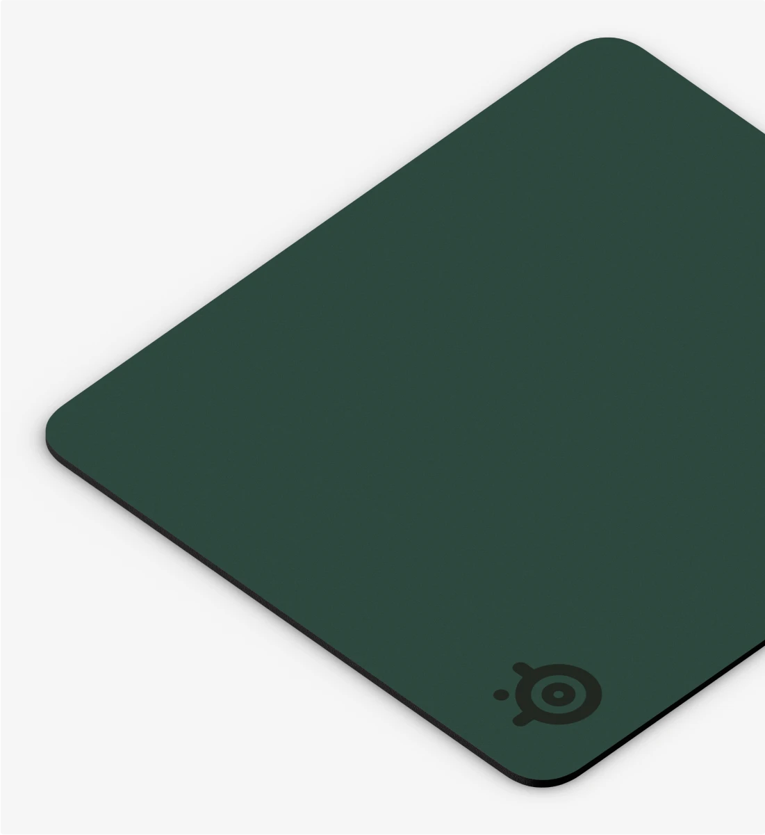 A close-up corner shot of a dark green SteelSeries QcK mousepad with the logo on a white background.