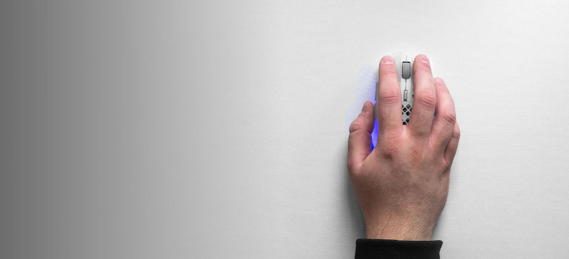 Top-down view of a hand using a white SteelSeries Aerox gaming mouse on a white QcK Heavy XXL mousepad, highlighting the smooth micro-woven cloth surface.