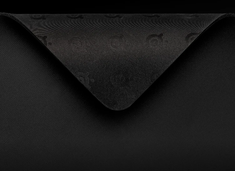 Uma foto em close-up do canto de um mousepad preto dobrado para revelar uma base de borracha antiderrapante com o logotipo da SteelSeries em relevo.