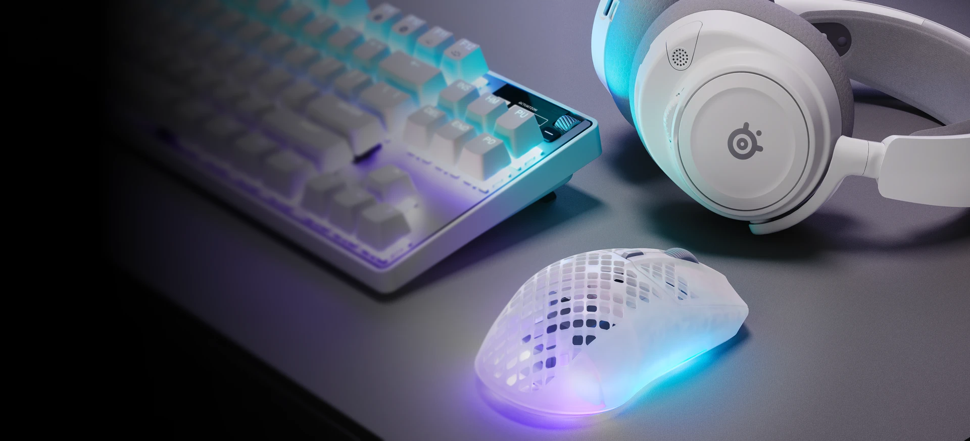 RGB keyboard, headset, and translucent gaming mouse on a desk in purple-blue lighting.