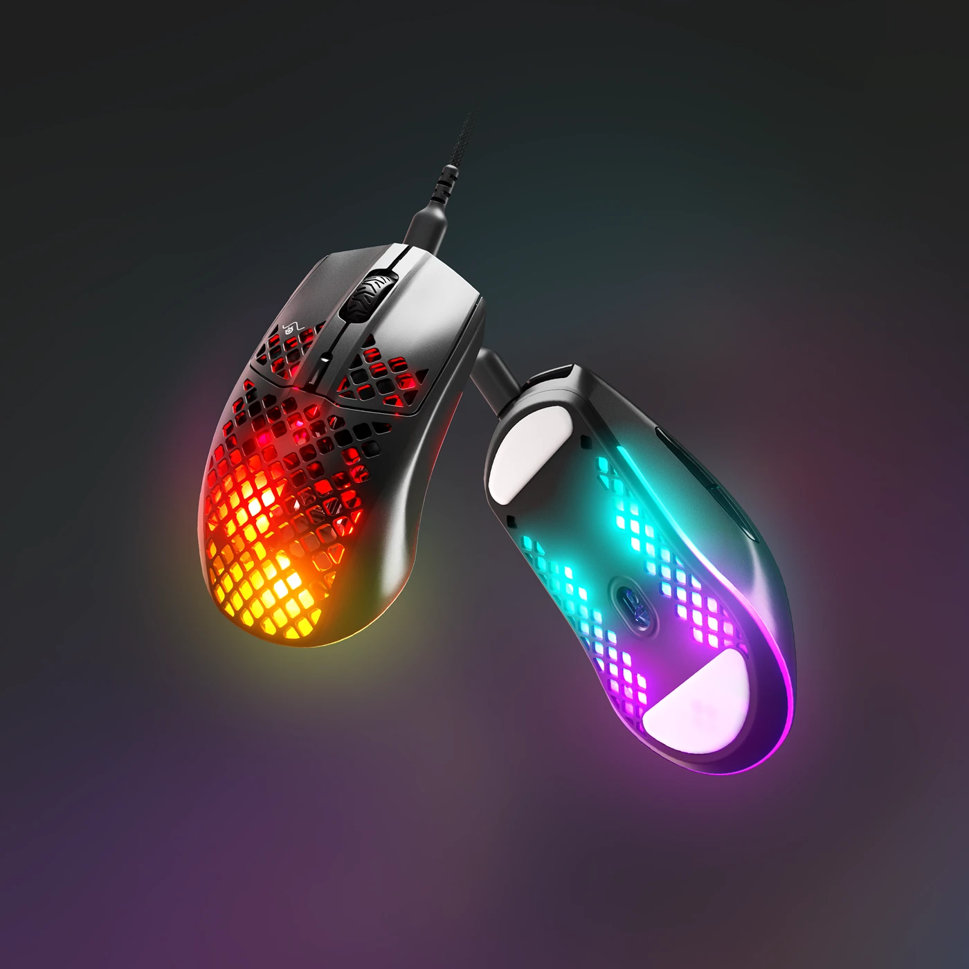 Un par de ratones de juego negros con luces arco iris que brillan a través de agujeros en forma de panal sobre un fondo oscuro.