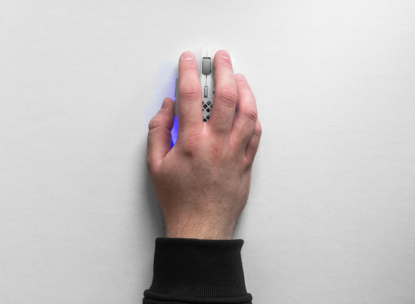 Top-down view of a hand using a white SteelSeries Aerox gaming mouse on a white QcK Heavy XXL mousepad, highlighting the smooth micro-woven cloth surface.