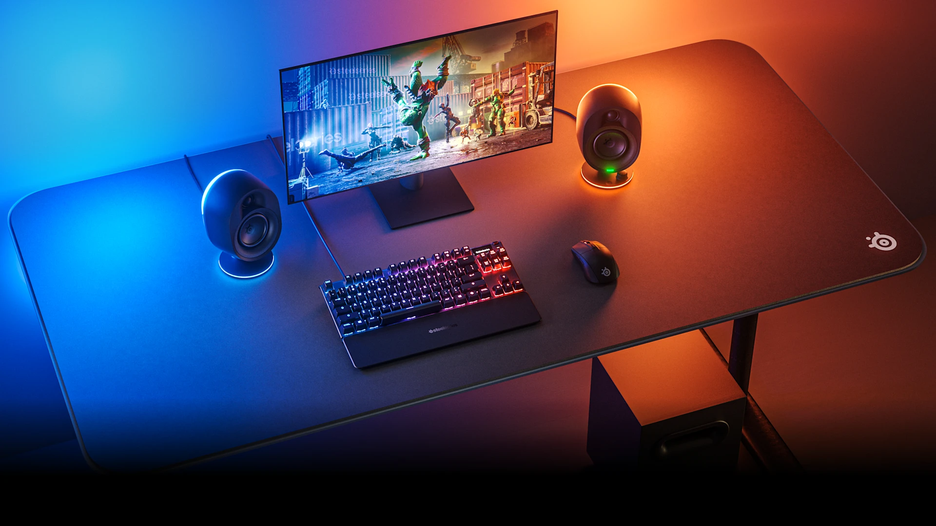 foto que muestra varios dispositivos SteelSeries sobre un escritorio iluminado con luces azules y naranjas.