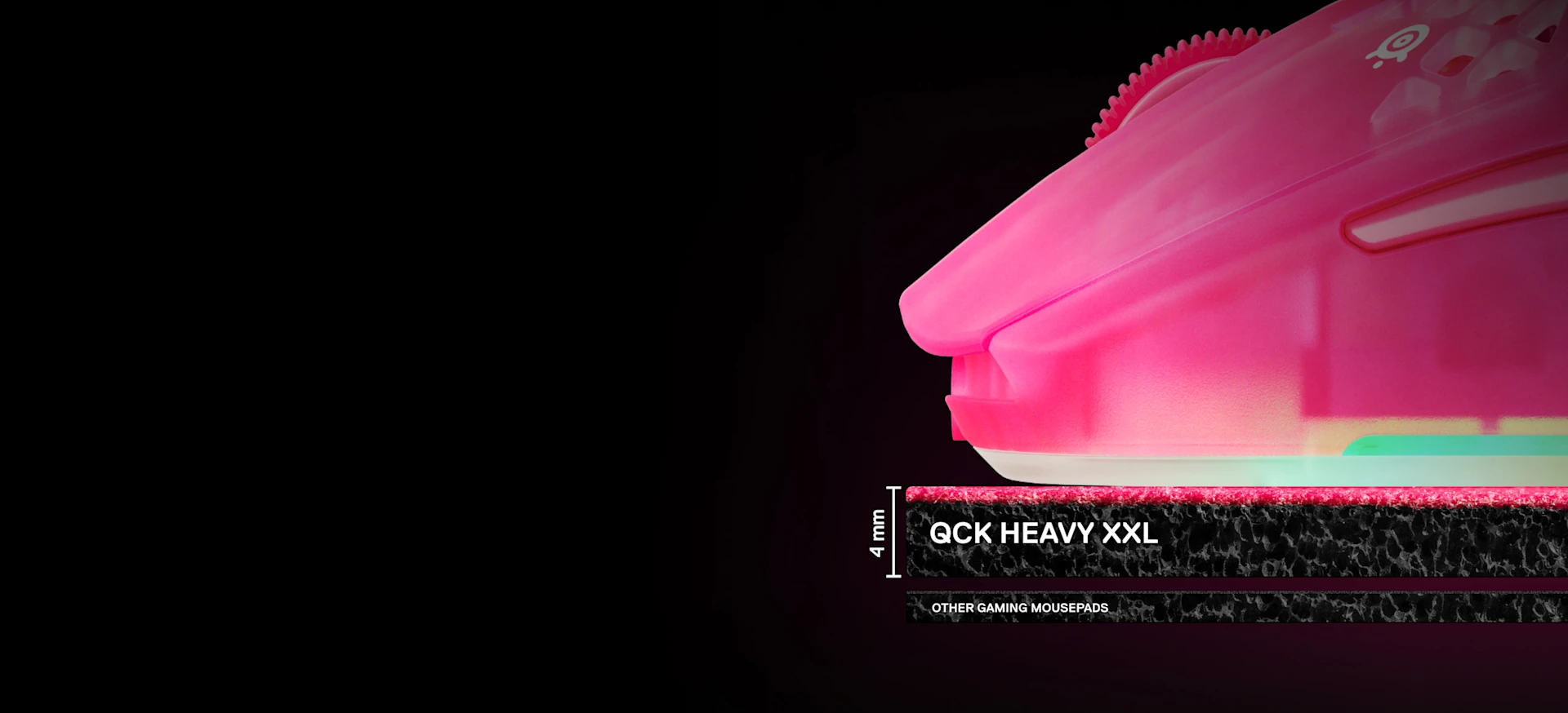 Una vista lateral en primer plano que muestra los 4 mm de grosor de la alfombrilla SteelSeries QcK Heavy XXL en comparación con las alfombrillas estándar más finas, con un ratón para juegos de color magenta apoyado encima.