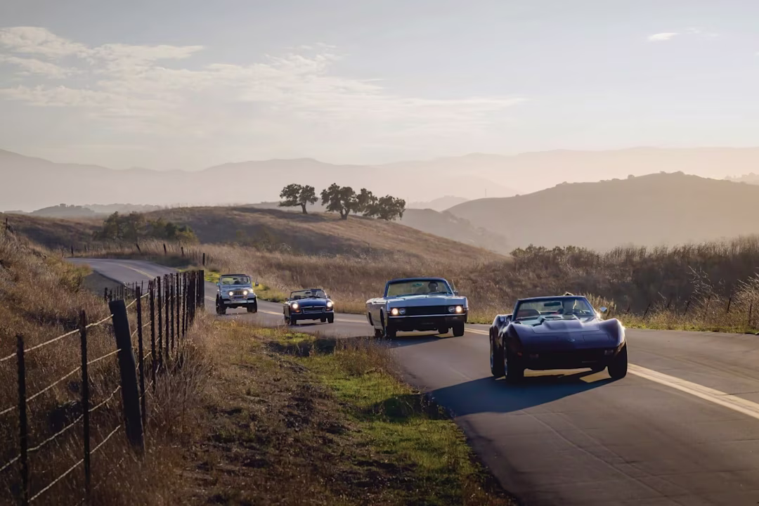 Vintage and super cars driving around mountain background.